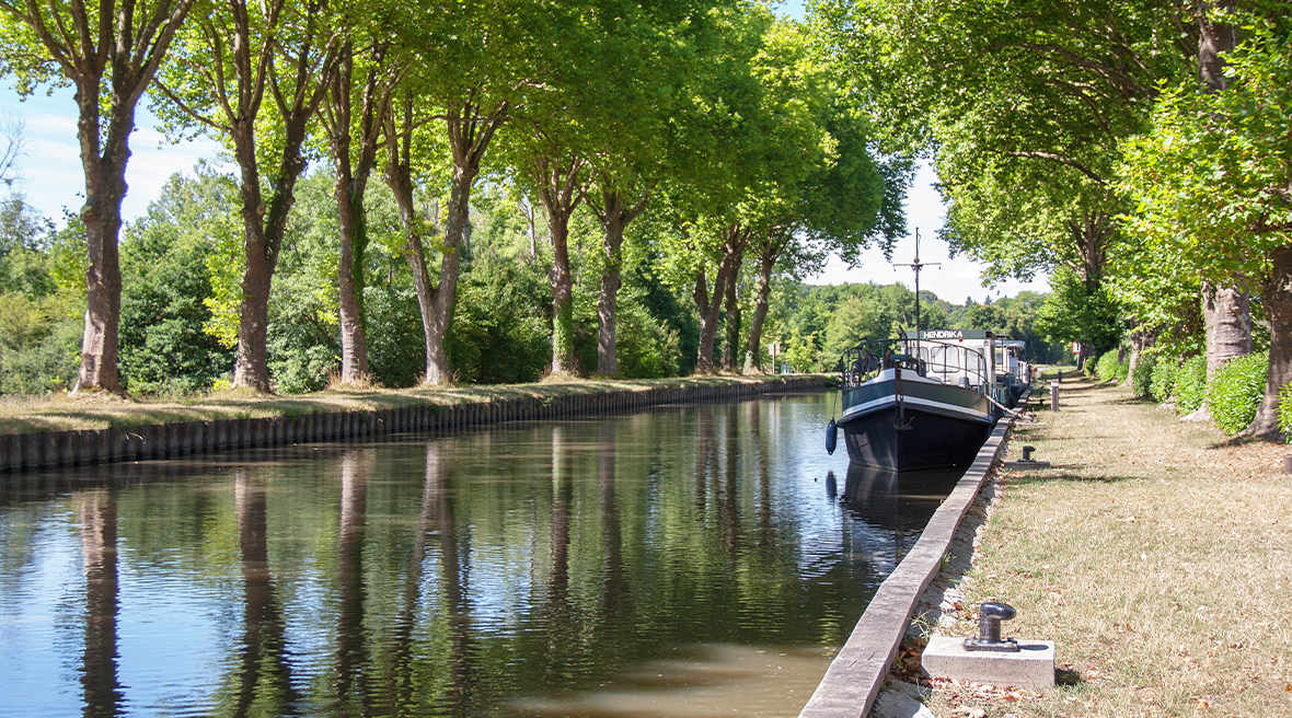 boat on the canal water lined with trees and stone path